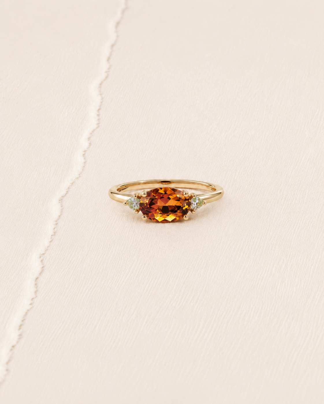 Bague en or jaune ornée d’une pierre orange et de deux pierres claires